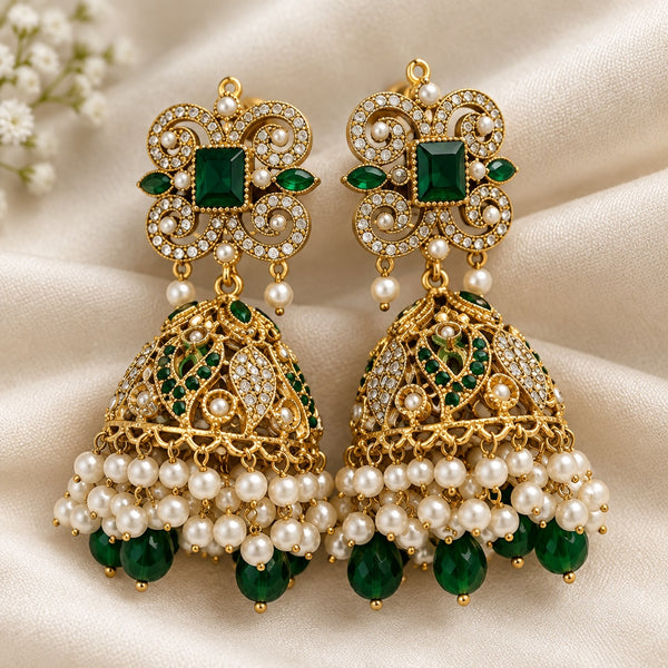 Pair of green and gold jhumka earrings with sparkling scrollwork, pearl-look fringe and green bead drops on ivory fabric