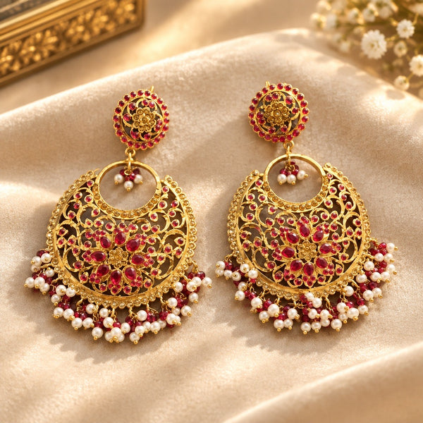 Red floral chandbali earrings with gold-tone filigree and pearl-style fringe on champagne fabric