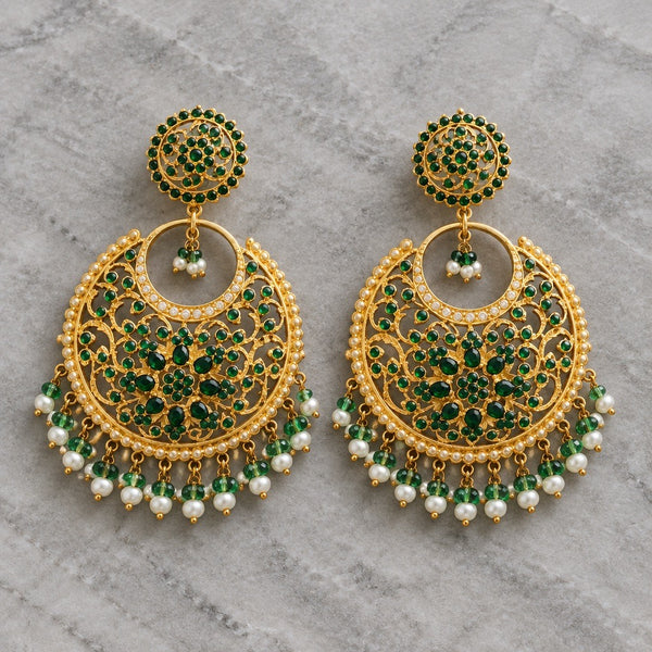 Green gold-tone chandbali earrings with floral stone details and white pearl-style bead drops on a gray background
