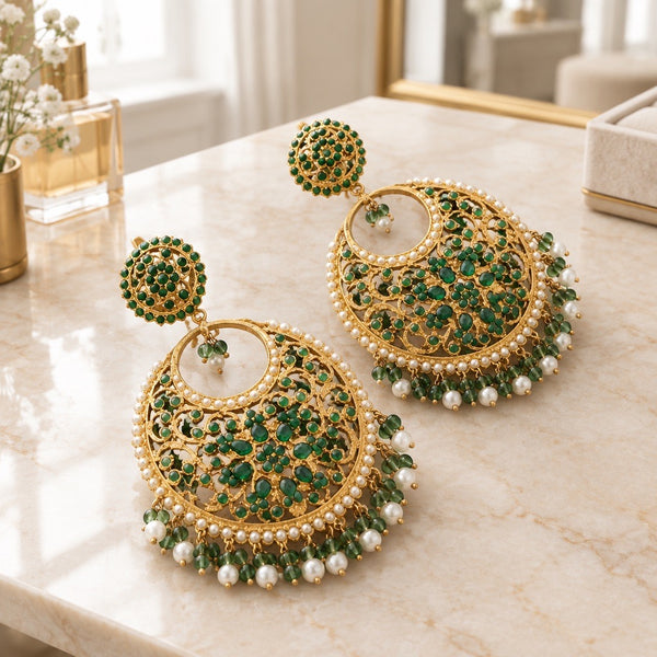Green floral chandbali earrings with gold-tone filigree and pearl-style fringe on a cream tabletop