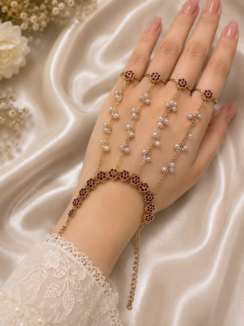 Adjustable gold-tone four-ring hand bracelet with maroon floral stones and pearl chain details