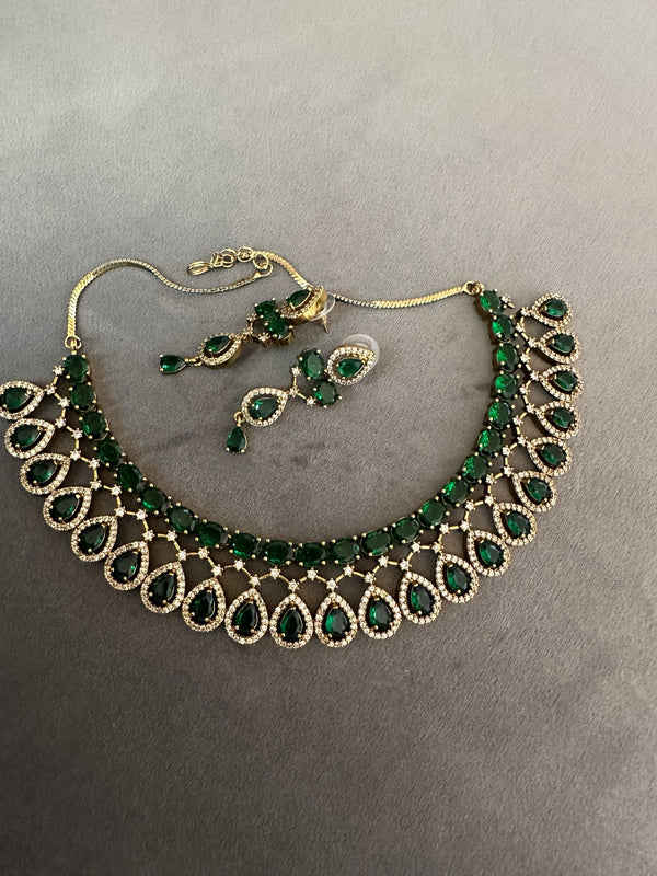 American diamond necklace and earrings set in emerald green flat lay with gold tone finish