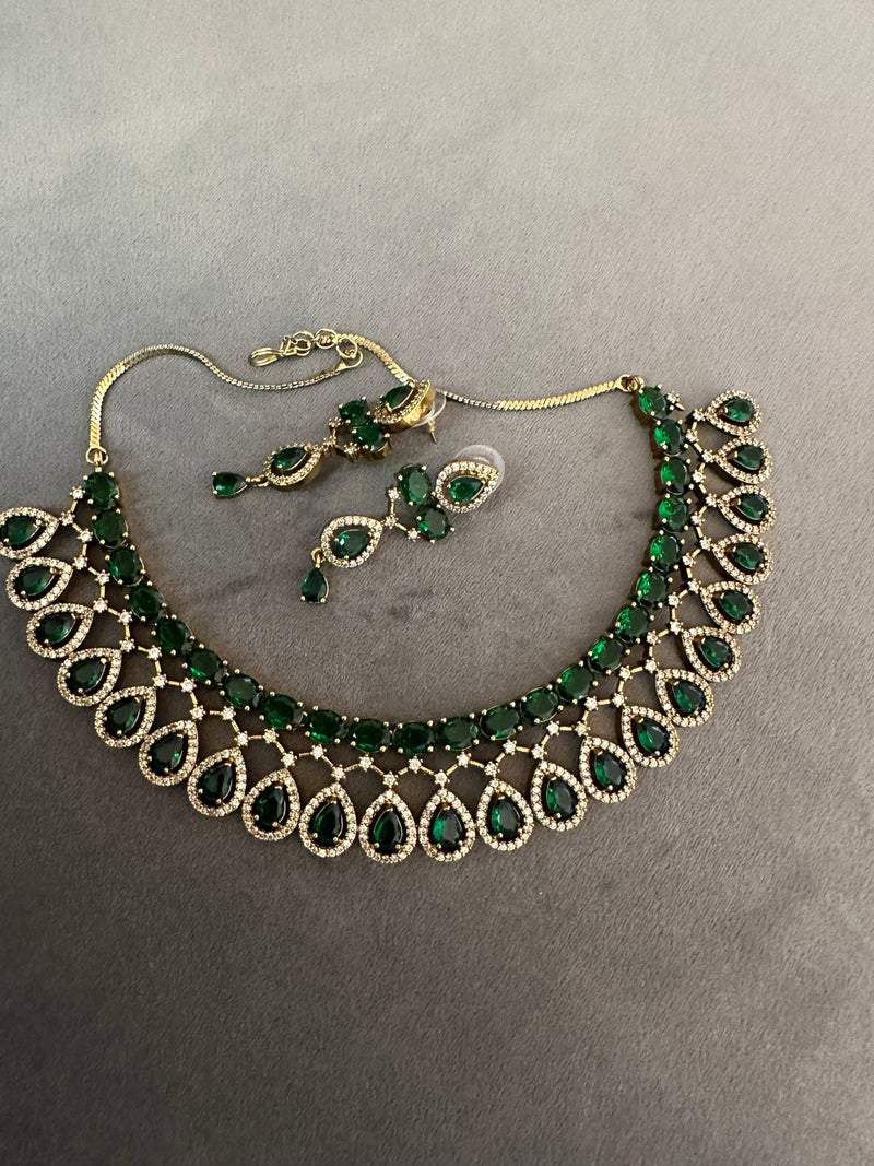 American diamond necklace and earrings set in emerald green flat lay with gold tone finish