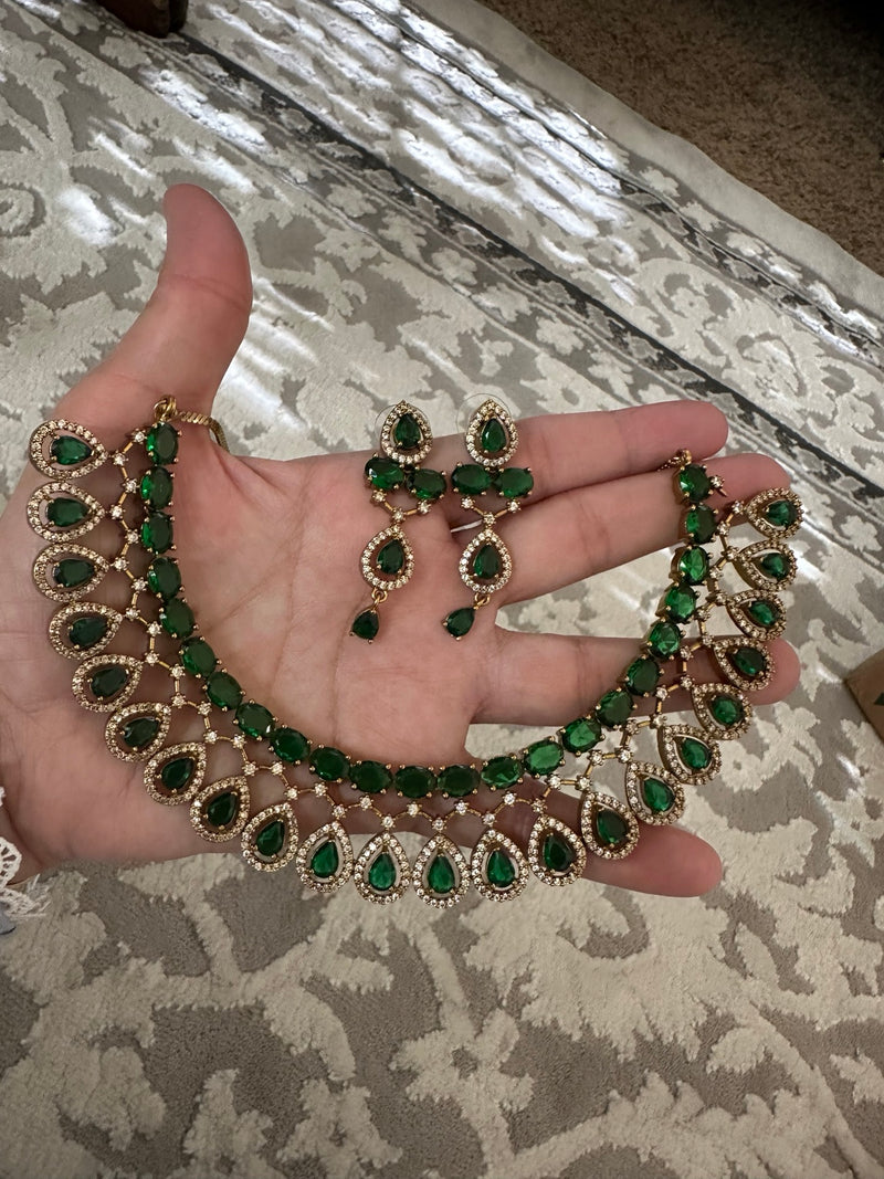 Emerald green American diamond necklace and earrings set shown on hand