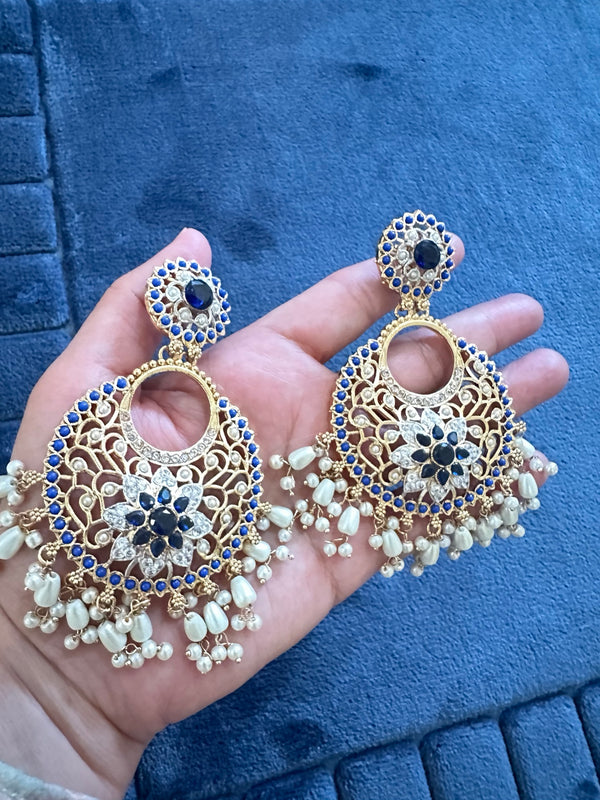 Blue and gold-tone floral chandbali earrings with openwork details and ivory bead fringe held in hand