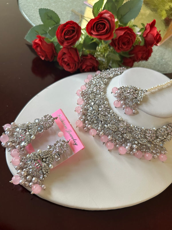 Angled view of blush pink American diamond choker necklace set with matching earrings and tikka