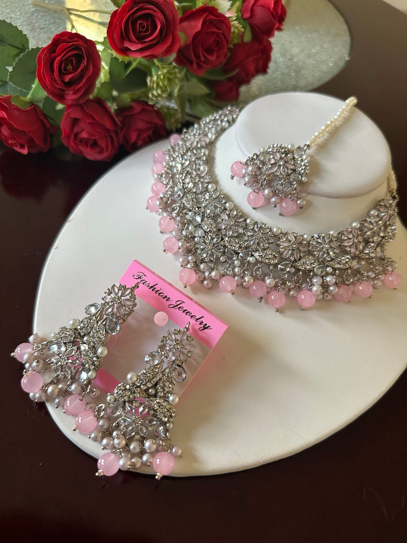 Blush pink American diamond floral choker necklace set with matching earrings and tikka displayed on a white jewelry bust