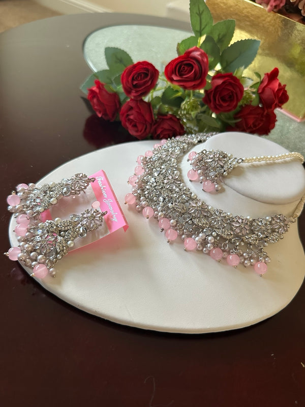 Side angled view of blush pink American diamond choker necklace set with matching earrings and tikka