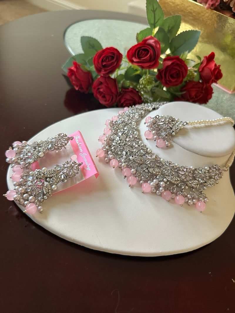 Side angled view of blush pink American diamond choker necklace set with matching earrings and tikka