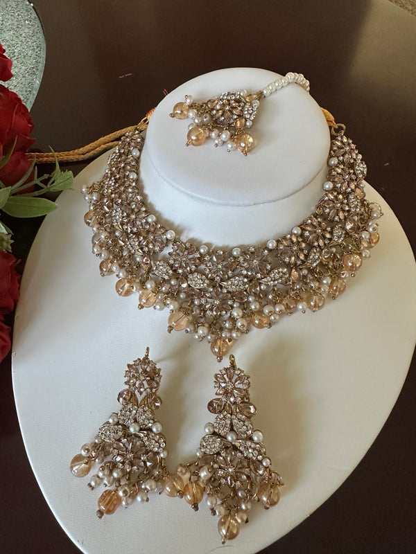 Close-up of champagne gold American diamond choker necklace with pearl accents and matching tikka