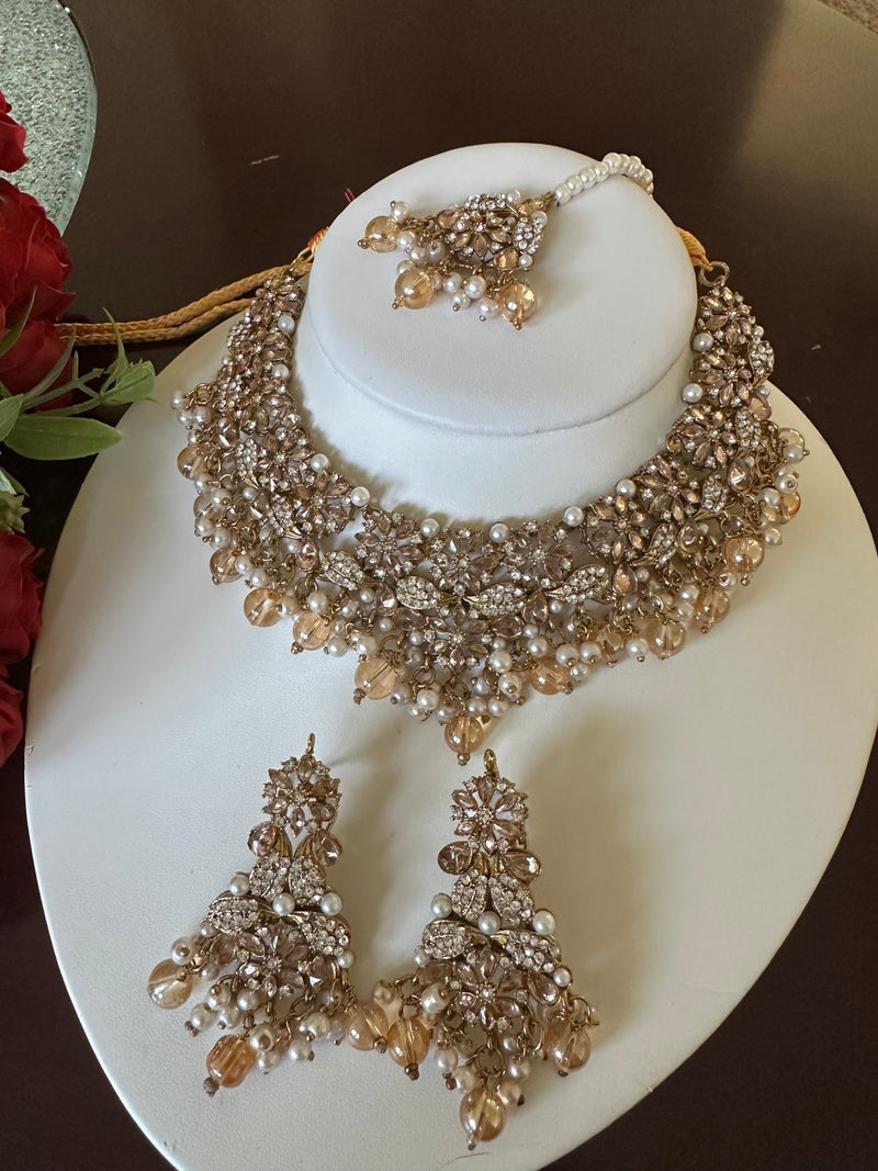 Close-up of champagne gold American diamond choker necklace with pearl accents and matching tikka
