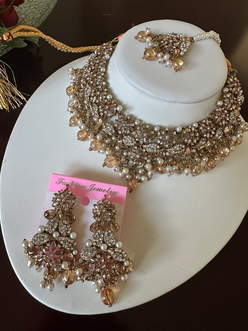 Champagne gold American diamond choker necklace set with matching long earrings and tikka on a white display