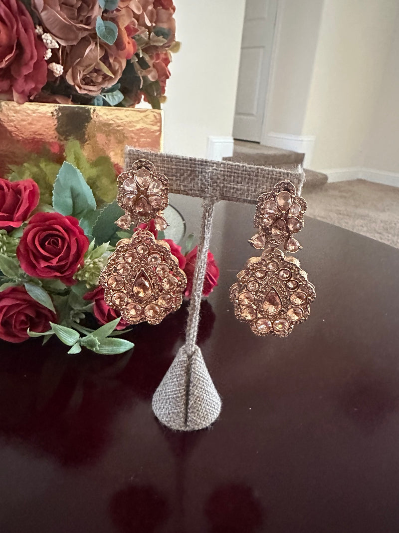 Close-up of champagne rose gold floral drop earrings with teardrop crystal details
