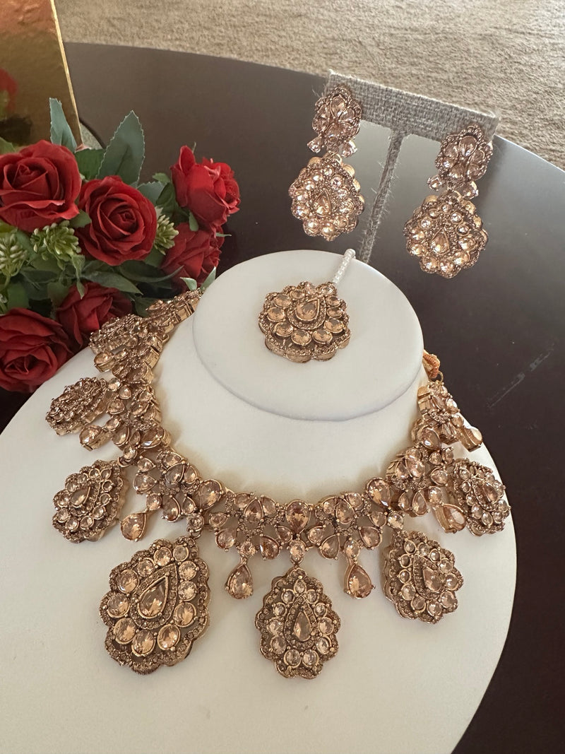 Full view of champagne rose gold necklace set with floral drop pendants, earrings and tikka