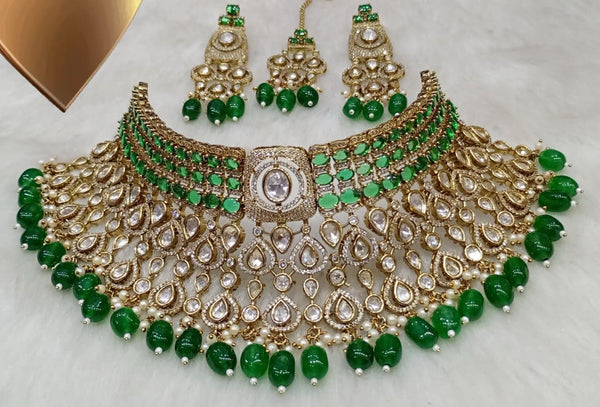 Emerald green Kundan bridal choker necklace set with matching earrings and maang tikka displayed on a white background