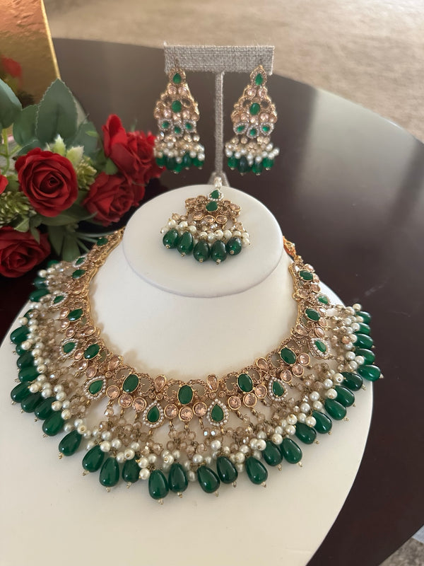Detailed emerald green kundan jewelry set with antique gold finish and pearl bead fringe