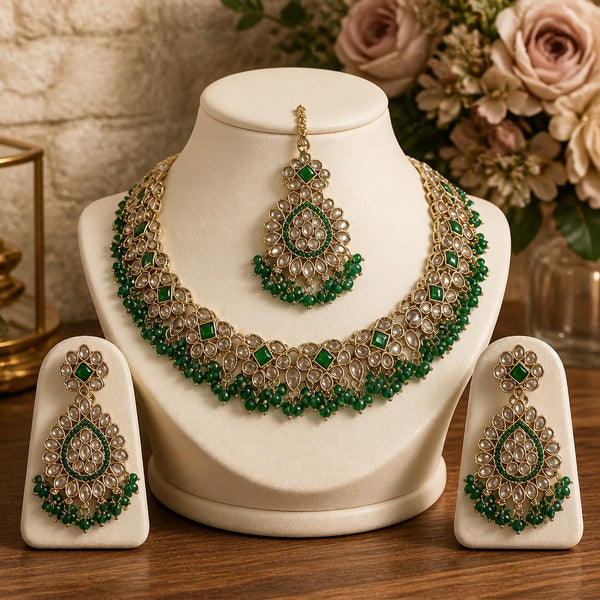 Gold and green kundan style necklace set with matching earrings and maang tikka