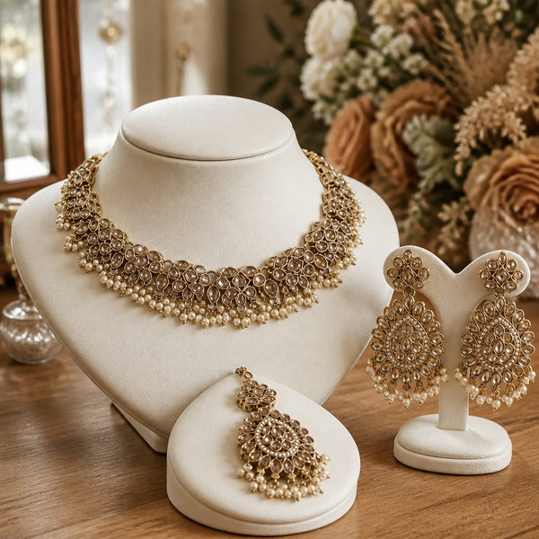 Gold and pearl kundan style necklace set with matching earrings and tikka