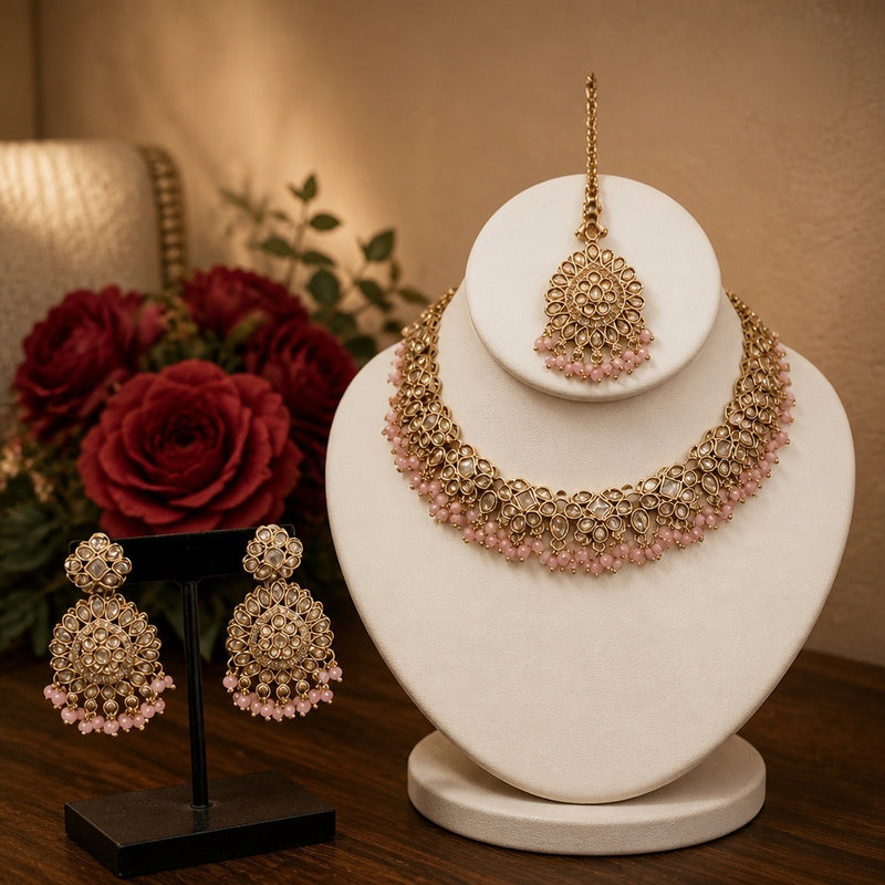 Gold and pink kundan style necklace set with earrings and maang tikka