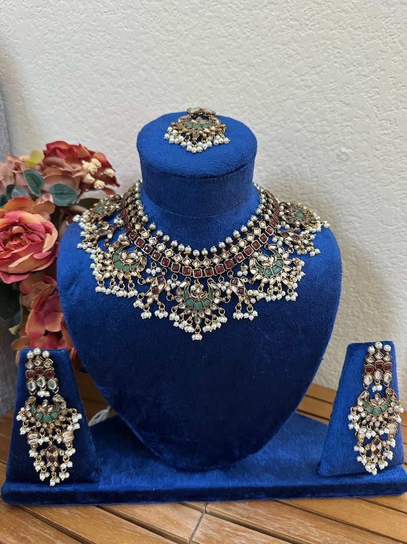Multicolor kundan bridal necklace set with earrings and tikka on blue velvet display