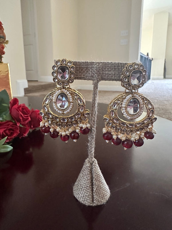 Close-up of matching maroon kundan statement earrings with pearl accents