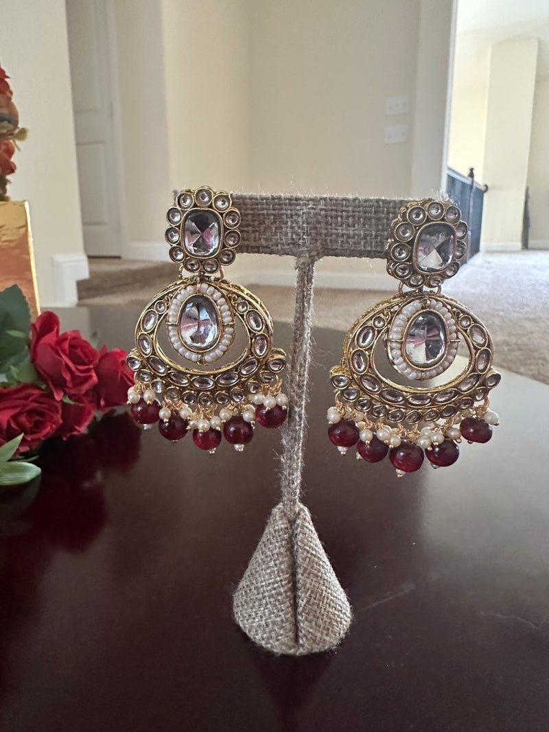 Close-up of matching maroon kundan statement earrings with pearl accents