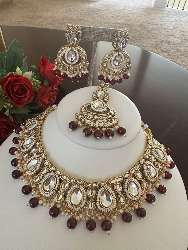 Front view of maroon kundan bridal necklace with pearl edging and bead drops