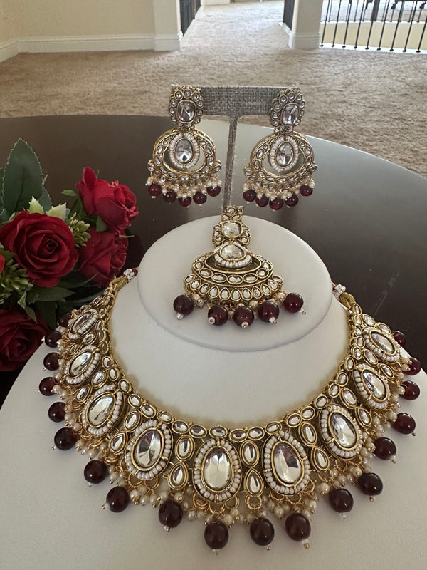 Full view of maroon kundan necklace set with matching earrings and tikka