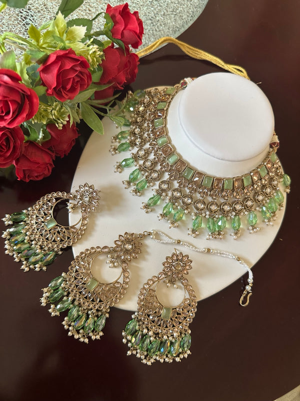 Mint green Kundan choker necklace set with matching earrings and tikka displayed on a white jewelry bust