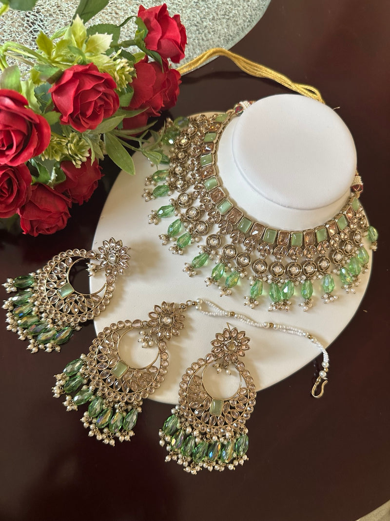 Mint green Kundan choker necklace set with matching earrings and tikka displayed on a white jewelry bust
