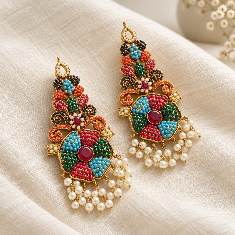 Pair of multicolor floral statement earrings with gold-tone scrollwork and pearl-look fringe on ivory fabric