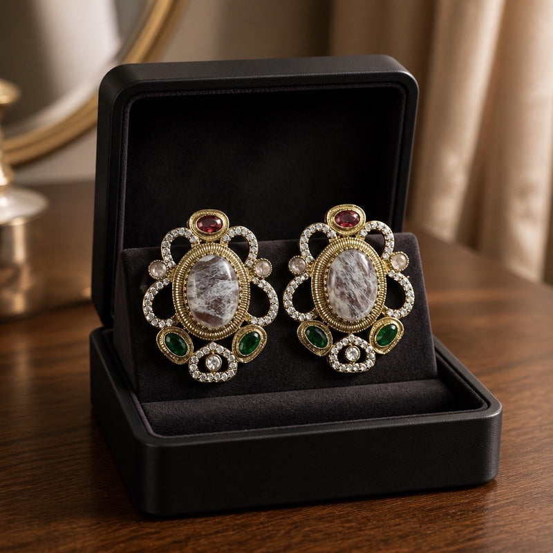 White oval stud earrings with emerald green accents in black luxury box