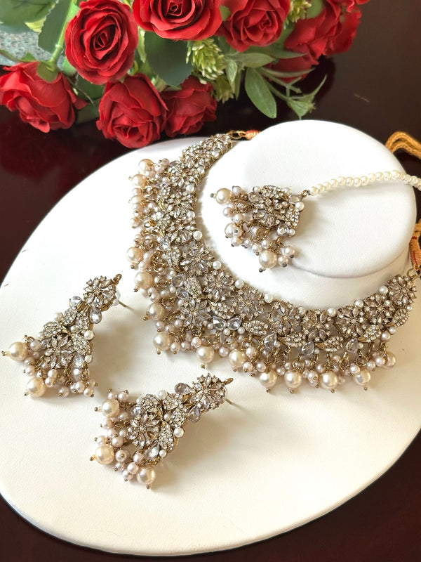 Detailed angled view of pearl and American diamond choker necklace, matching drop earrings, and tikka