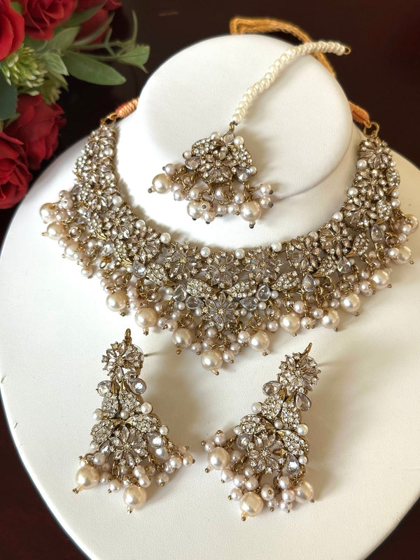 Pearl and American diamond floral choker necklace set with matching earrings and tikka displayed on a white jewelry bust