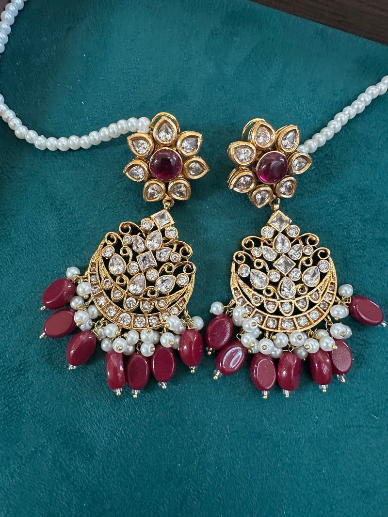 Ruby kundan chandbali earrings on teal background with pearl strand