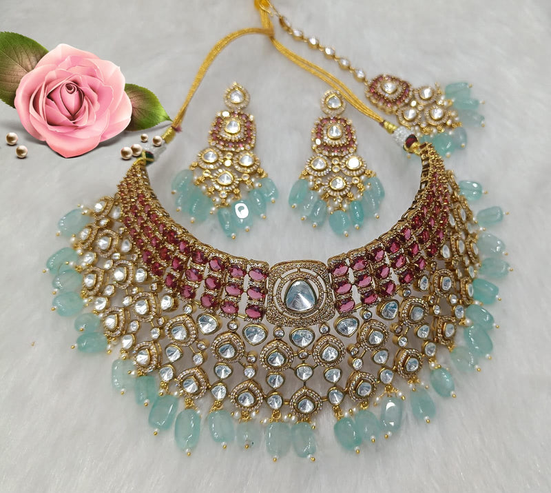 Ruby pink and mint green Kundan choker necklace set with matching earrings and maang tikka displayed on a white background