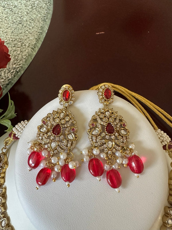 Close-up of matching ruby red Kundan bridal earrings with pearl and red bead drops
