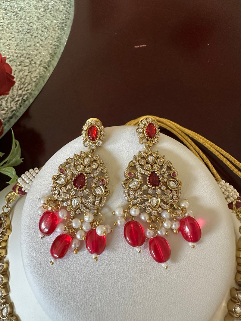 Close-up of matching ruby red Kundan bridal earrings with pearl and red bead drops