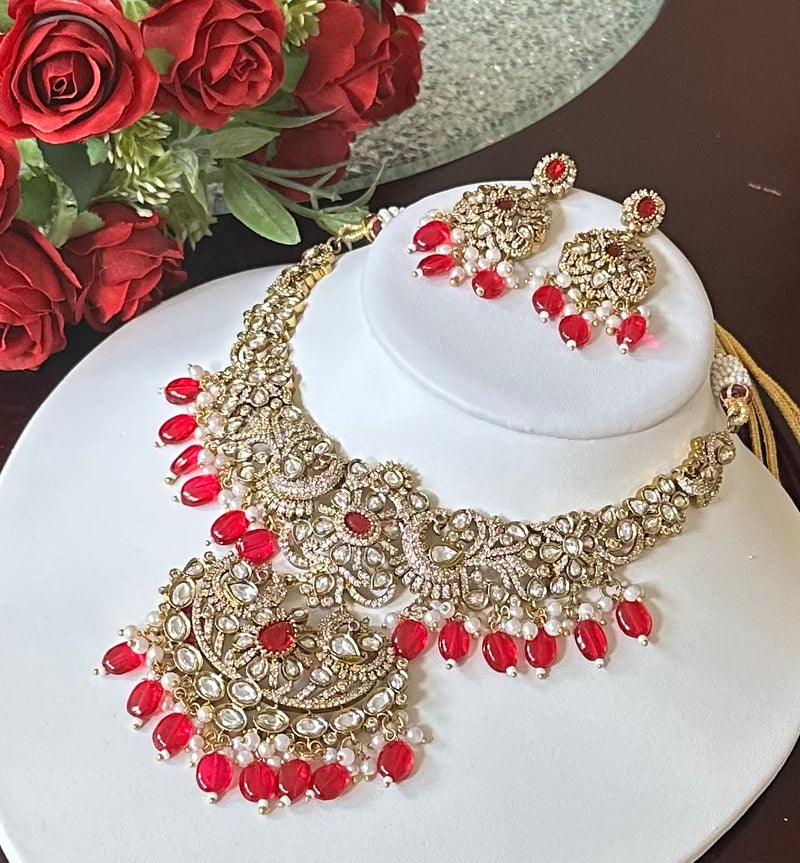 Ruby red Kundan bridal necklace and matching earrings shown from an angled view on a white display
