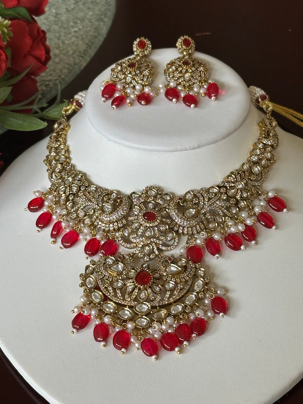 Ruby red Kundan bridal necklace set with matching earrings displayed on a white jewelry bust