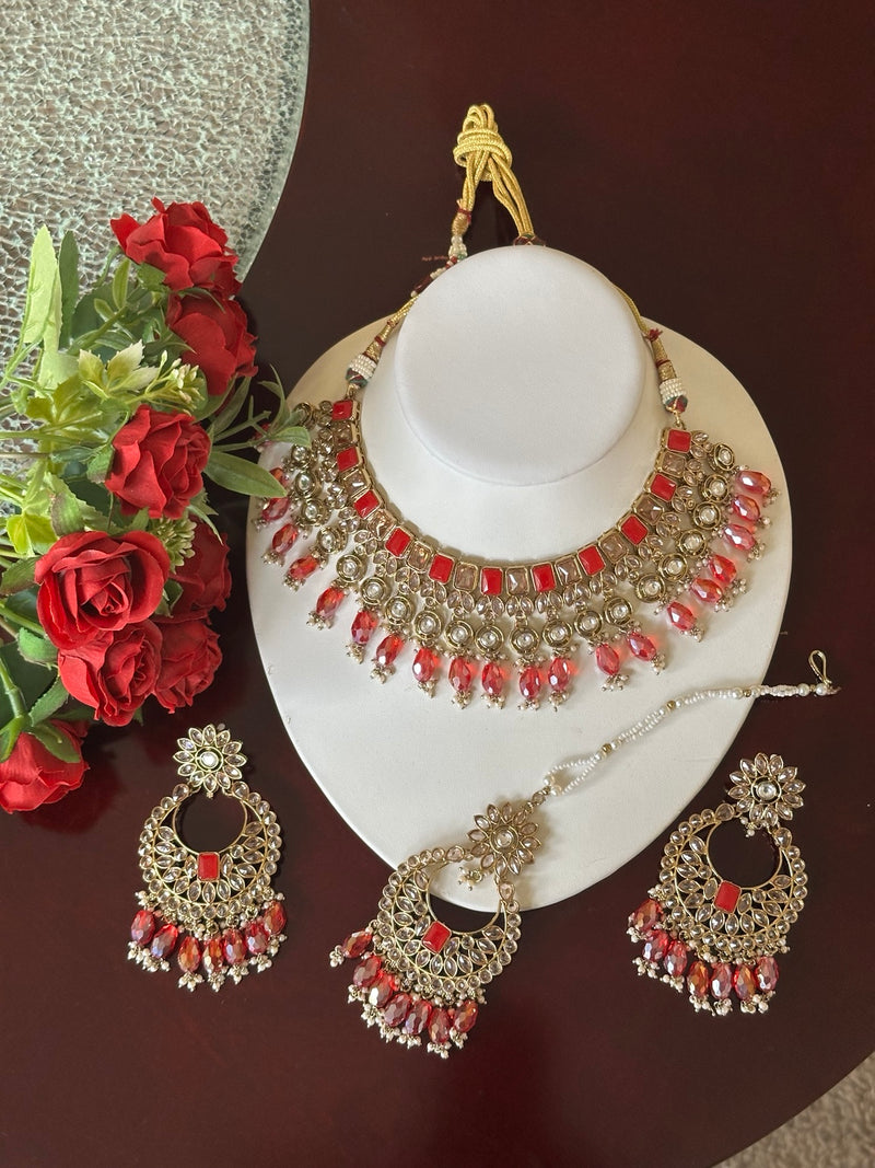 Ruby red Kundan choker necklace set with matching earrings and tikka displayed on a white jewelry bust