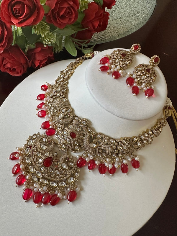 Detailed angled view of ruby red Kundan bridal necklace set with matching earrings and pearl accents