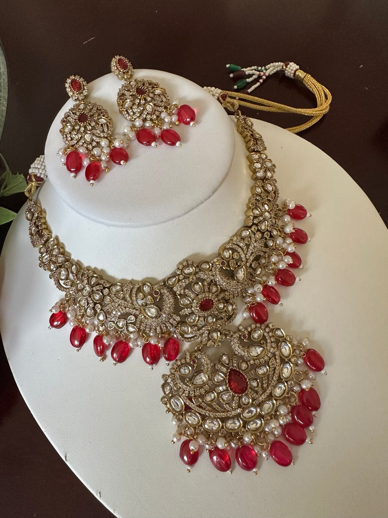 Full view of ruby red Kundan statement necklace set with matching earrings and pearl accents