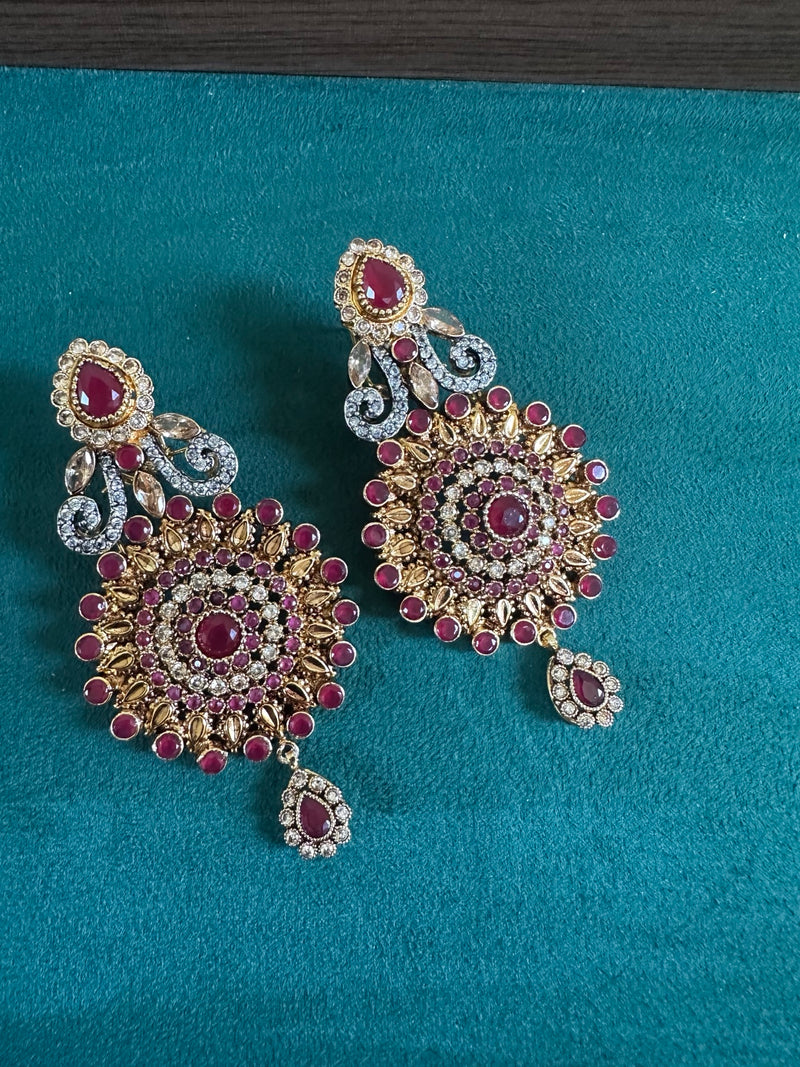 Ruby statement earrings on teal background with gold tone detailing
