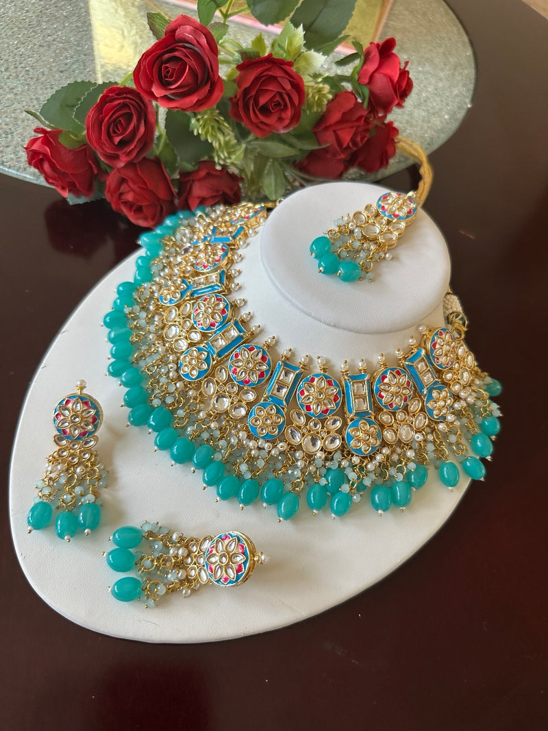 Turquoise blue Kundan choker necklace set with matching earrings and tikka displayed on a white jewelry bust